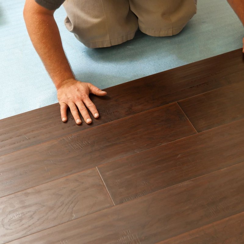 flooring installer installing hardwood planks